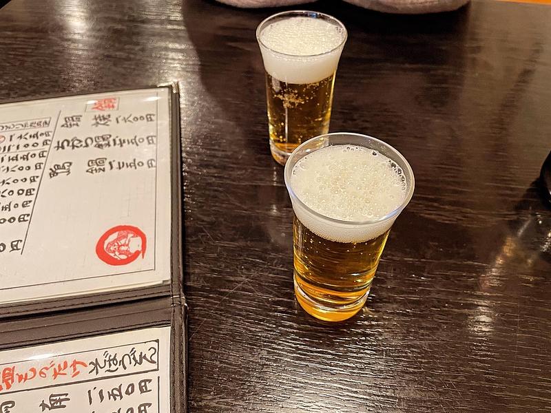 テーブルにメニューとグラスビールが二つ